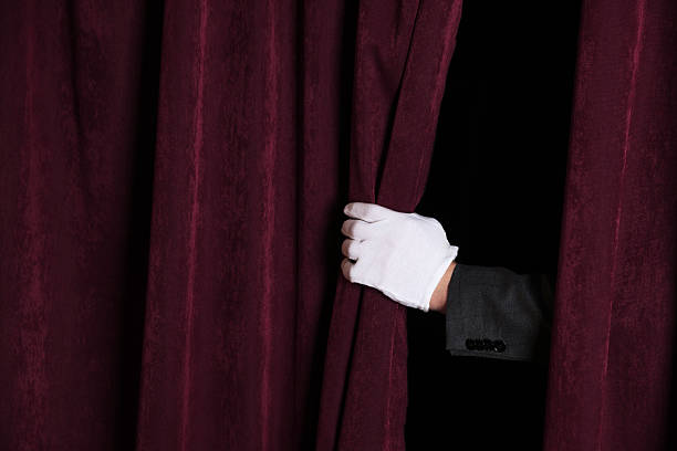 istock Man closing red front curtains in theatre, closeup 2228381504