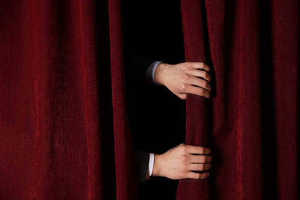 istock Man closing red front curtains in theatre, closeup 2228381520