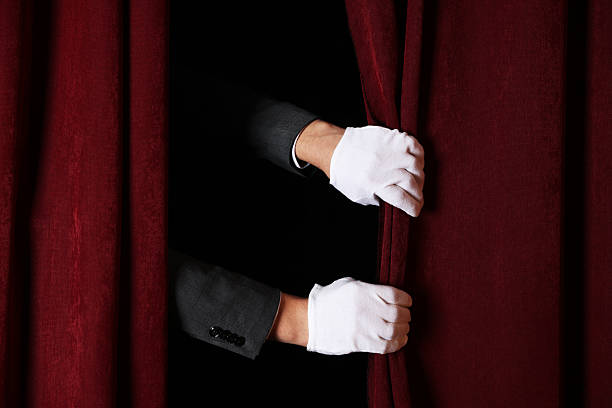 istock Man closing red front curtains in theatre, closeup 2228381521
