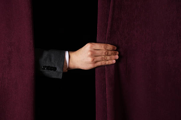 istock Man closing red front curtains in theatre, closeup 2228381523