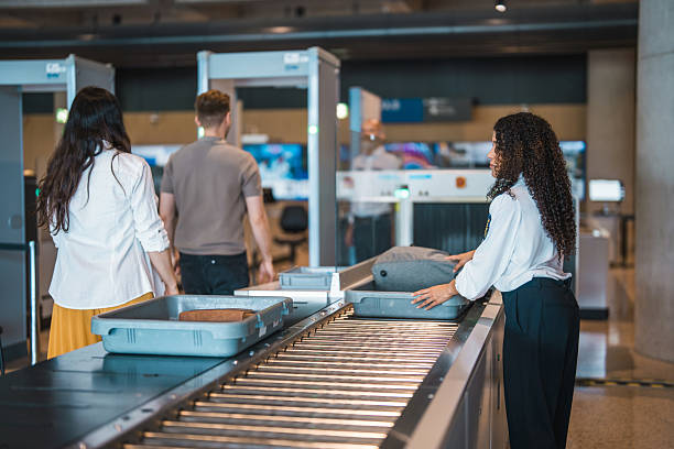 istock Young Hispanic Female Airport Security Worker Inspecting Luggage at Checkpoint with Passengers 2228382687