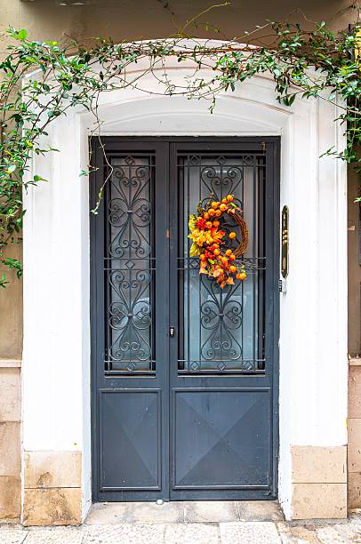 An elegant autumn wreath featuring pinecones, orange accents, and dried foliage adorning a charming yellow door in Cobh, Ireland, showcasing seasonal decoration and a warm aesthetic