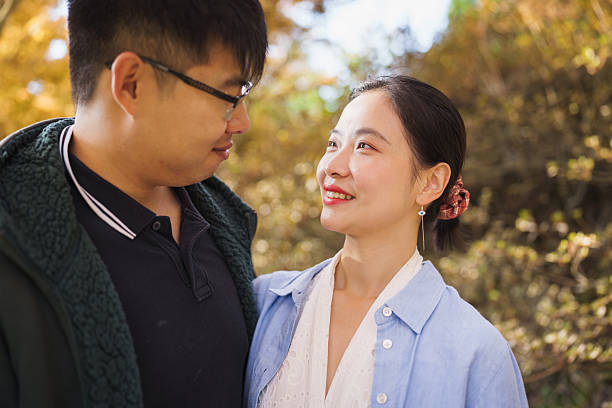 Their eyes meet in a tender moment as soft autumn light glows around them.