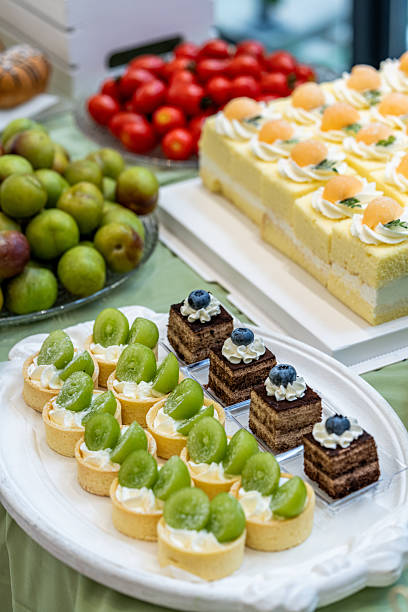 This is a photo of a cake - like dessert garnished with fruits. Each dessert, which is a single - serving mini - cake or pie, is topped with a fruit. This photo can be categorized into dessert, party food, event catering, sweets, fruity desserts, and gourmet food.