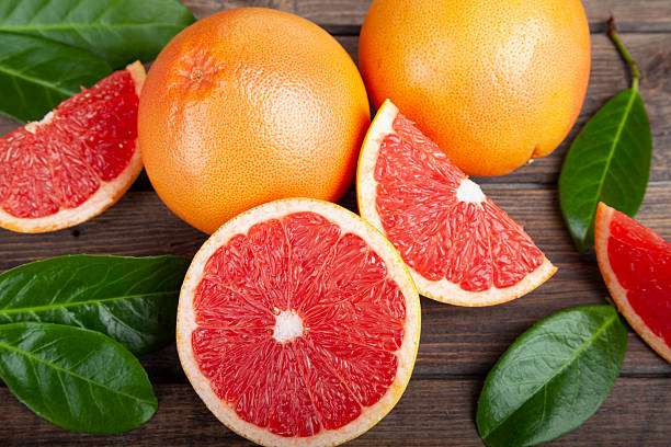 istock Ripe grapefruits with green leaves on brown rustic wooden table 2228399742