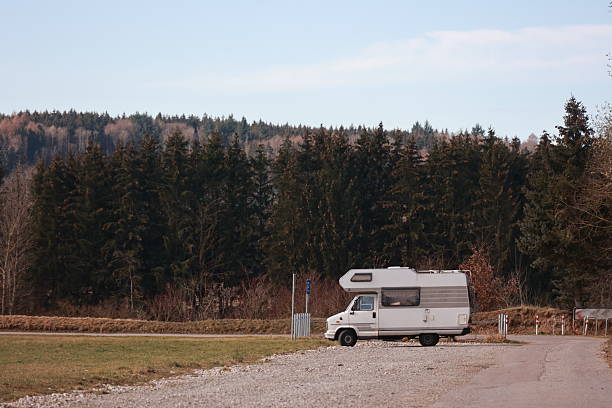 istock White camper van is parked in a field next to a road 2228408394