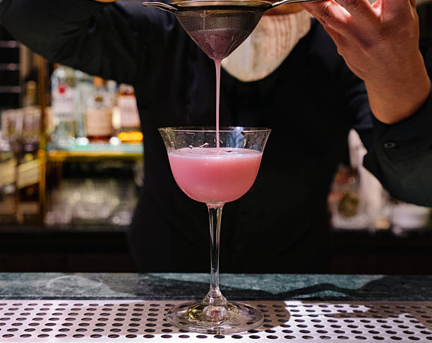 istock Pink Cocktail Being Strained Into Glass by Bartender at Bar 2228409186