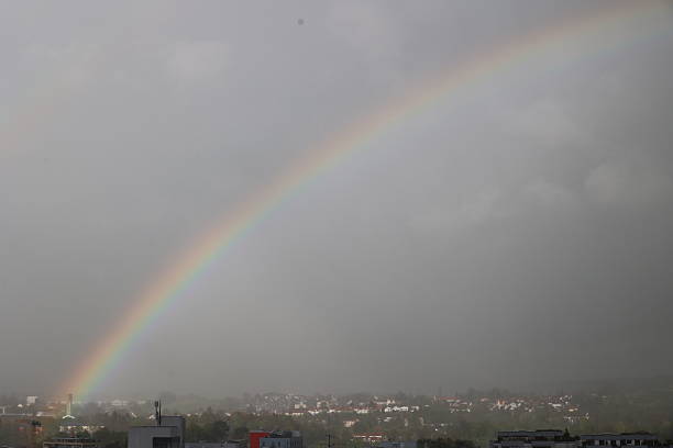 Lush green nature in May, rainbow above a village