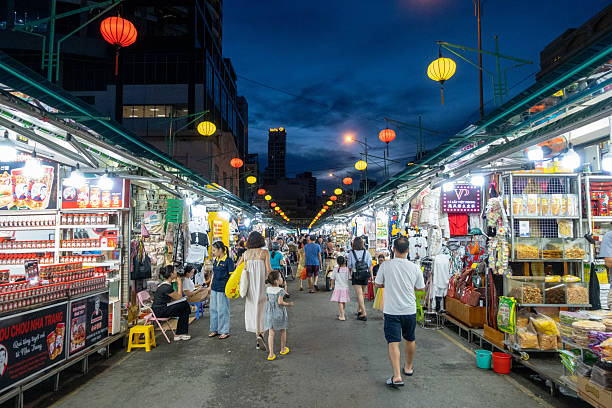 Bustling night asian market with food stalls, lanterns, and shoppers under a twilight sky in Nha Trang, Vietnam