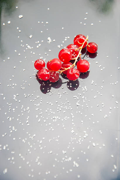 bunches of ripe red currants sprinkled with sugar on a black ceramic board