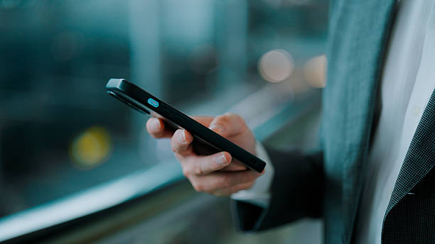 istock Young Asian man in suit using phone while going upstairs at an airport. 2228418495