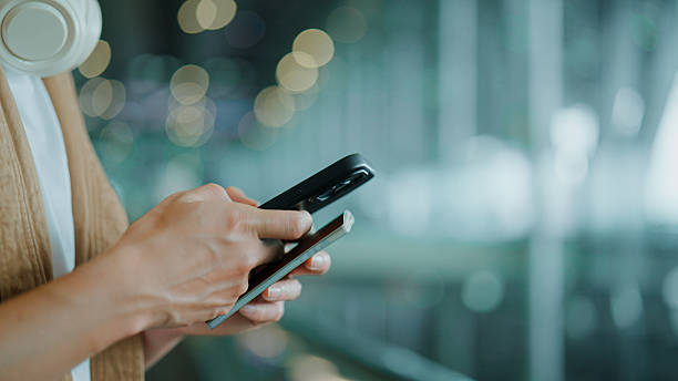 istock Young Asian man using mobile phone while going up moving walkway and holding passport in hand at an airport. 2228418576