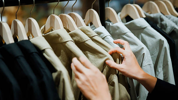 istock Man browsing through selections of clothes on a rack while shopping in a mall. 2228418745