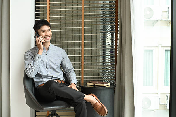 istock A man is sitting in a chair and talking on his cell phone. He is smiling while talking 2228421849