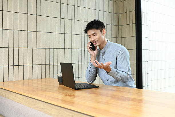 istock A man is talking on his cell phone while sitting at a desk. 2228422130
