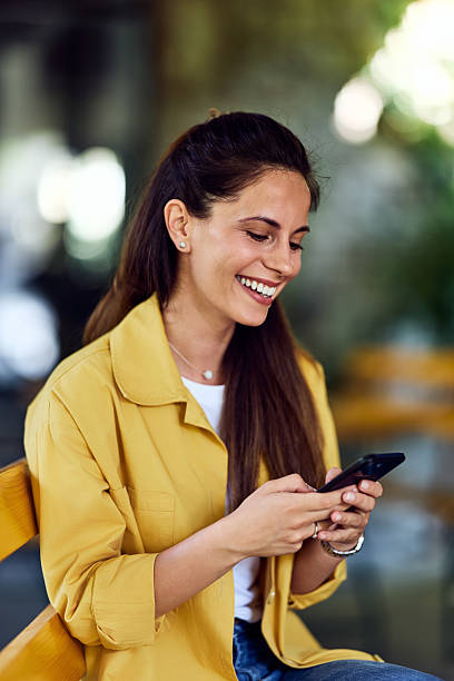 istock Woman Smiling While Using Smartphone Outdoors on a Sunny Day 2228425416