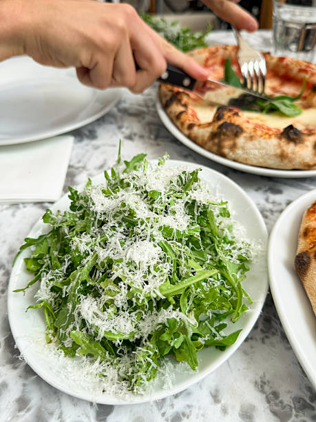 Image of eating green salad with rocket leaves, parmesan / al fresco dining outdoors, enjoying fresh arugula, healthy meal,  pizza