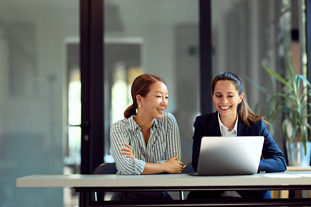 istock Two Professional Women Smiling While Collaborating on a Laptop in a Modern Office 2228426398