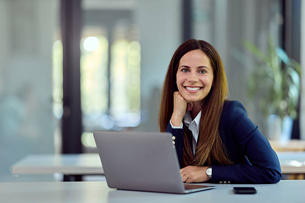 istock Confident Businesswoman Smiling While Working on Laptop in Modern Office Environment 2228426404