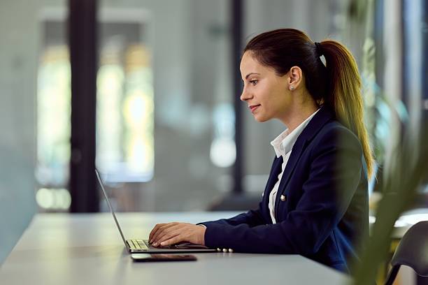 istock Businesswoman Working on Laptop in Office Setting with Natural Light 2228426439