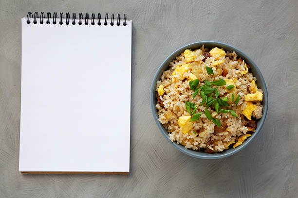 istock Homemade Fried Rice with Bacon and Egg in a Bowl, blank notepad, top view. Flat lay, overhead, from above. Copy space. 2228427963