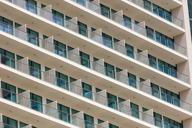 A tall building with many windows and balconies. The windows are open, letting in a lot of light