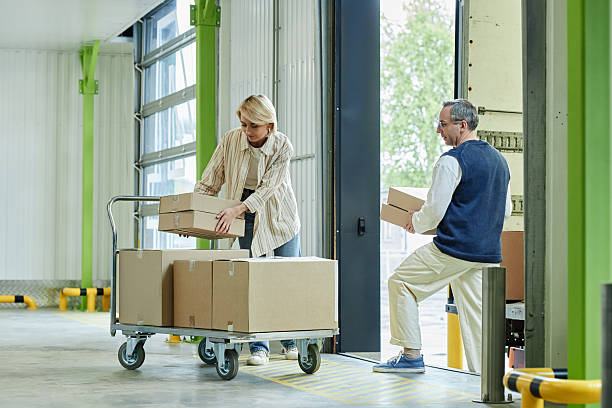 istock Middle Aged Caucasian Woman and Man Loading Cardboard Boxes in Warehouse 2228437625