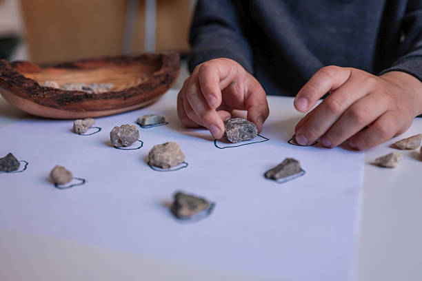 istock Child sorting small natural stones onto drawn circles on white paper. Educational and sensory activity promoting fine motor skills, focus, and nature-based learning at home 2228438662