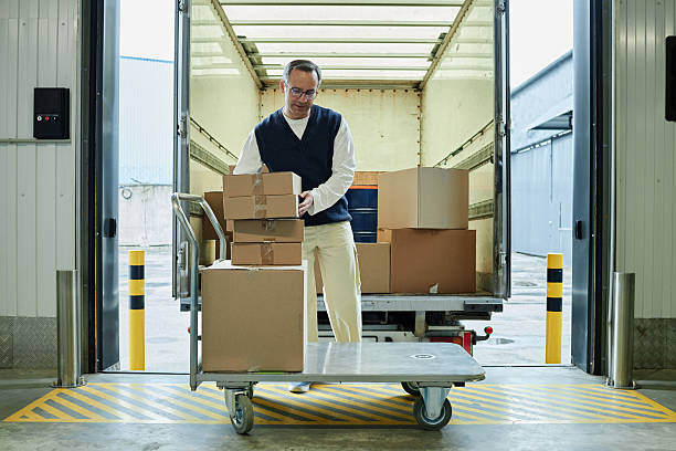 istock Middle Aged Caucasian Man Unloading Cardboard Boxes from Delivery Truck 2228439531