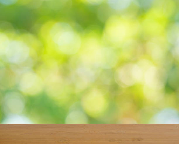 istock Empty brown wooden table surface for product placement with bokeh from green leaves bush in background 2228442216