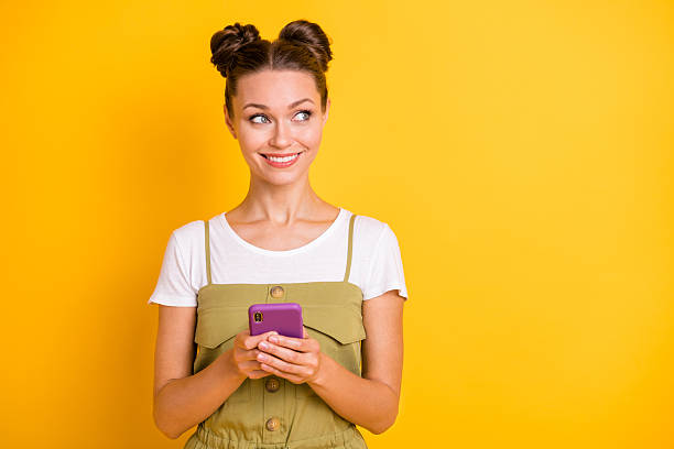 istock Portrait of attractive curious cheerful girl using gadget looking aside copy space comment isolated over bright yellow color background 2228448021