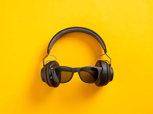 istock Wireless black headphones and sunglasses lying on yellow background 2228450027
