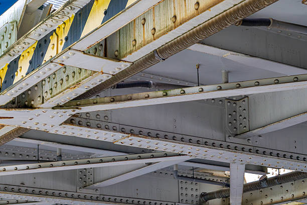 istock Steel bridge structure detail with visible rivets, signs of rust, and technical cables, viewed from underneath. 2228451557