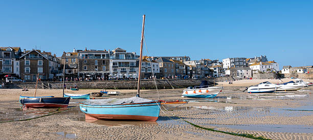 many boats on dry sand in harbour of st ives at low tide on sunny day in spring