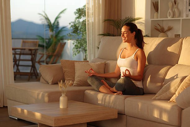 istock Happy yogi doing yoga on a sofa at sunset at home 2228456099