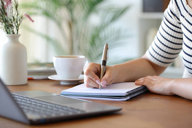 istock Woman hand writing on notebook beside laptop 2228457214