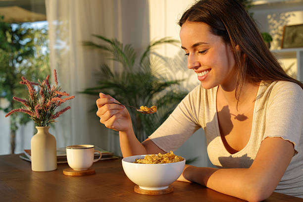 Happy woman in the morning at home eating cereals stock photo