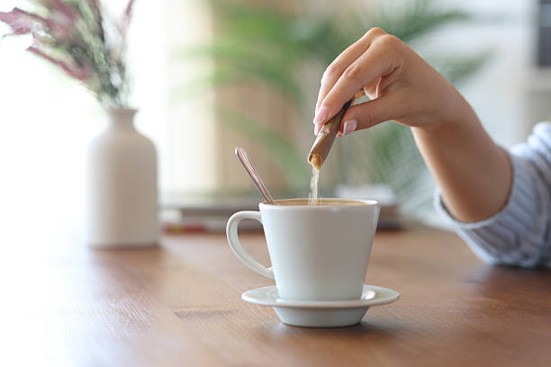 istock Woman hand throwing sugar in a coffee cup at home 2228457841