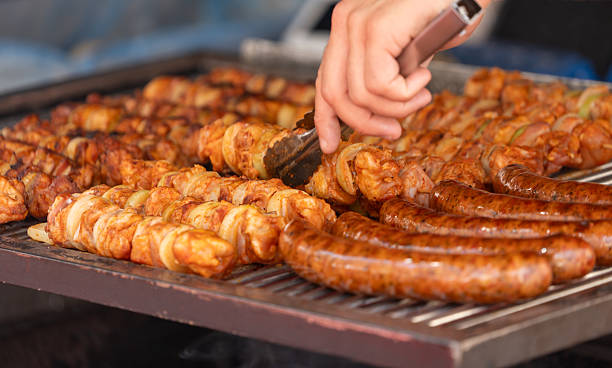 istock Grilled sausages on a grill with human hand 2228460894