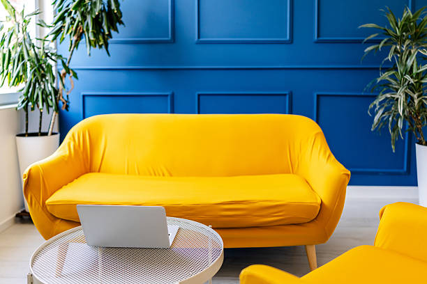istock Bright yellow couch and laptop create a modern indoor workspace in a cozy room filled with plants 2228461827
