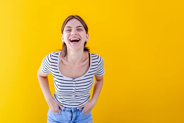 istock Young woman laughing joyfully in a bright yellow room while standing with her hands on her hips 2228466281