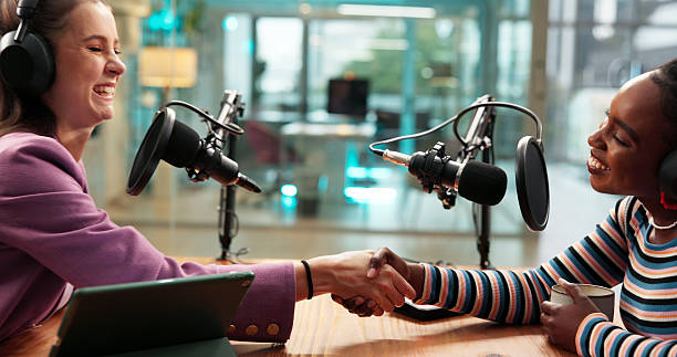 istock Podcast interview, host or guest with handshake in studio for welcome, talk show or radio broadcast. Media production, content creation and happy women with shaking hands for greeting and live stream 2228467446