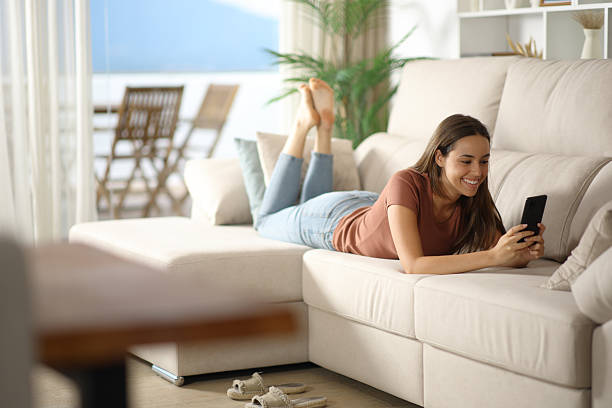 istock Happy woman using cell phone in a living room 2228468473