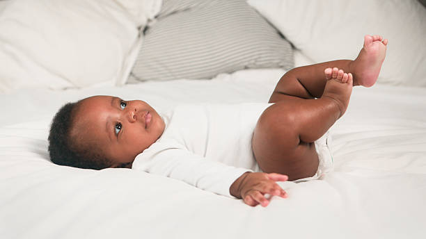 istock Adorable Baby Relaxing on a Cozy White Bed in a Bright Home Interior 2228468778