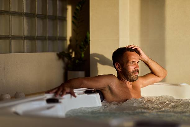 istock Man Relaxing in a Hot Tub During Sunset in a Cozy Indoor Setting 2228469905