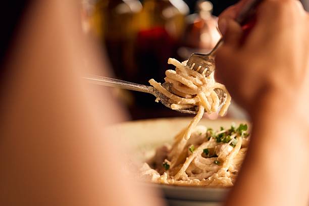 istock Close-Up of Hands Twisting Pasta Using Fork and Spoon at a Restaurant 2228469923