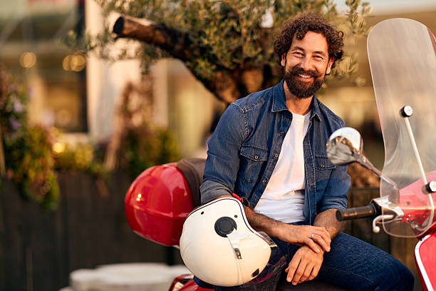 istock Smiling Bearded Man Relaxing Outdoors with Scooter and Helmet in Urban Setting 2228469931