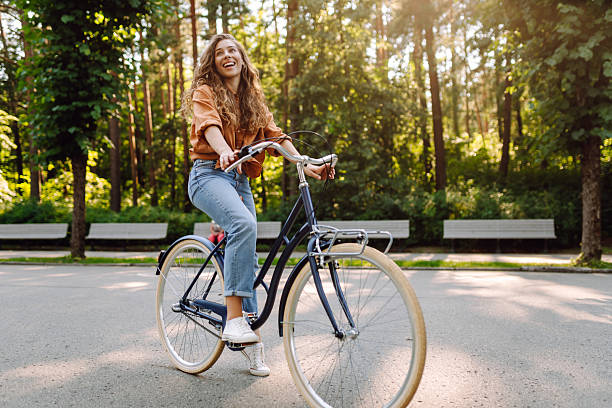 istock Cheerful woman with a bicycle in a sunny park. 2228471018
