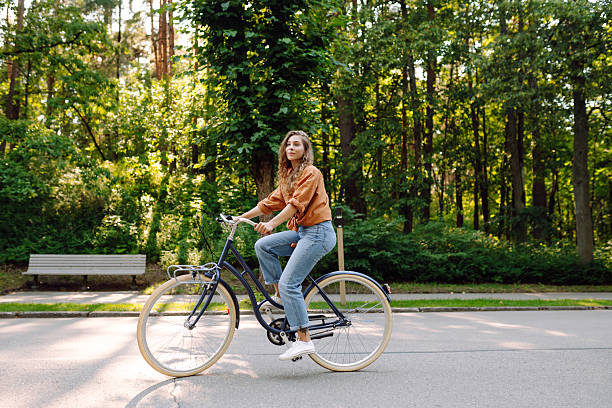 istock Cheerful woman with a bicycle in a sunny park. 2228471030