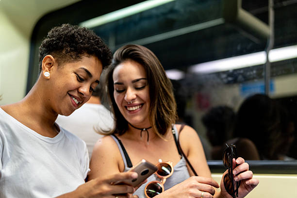 istock Smiling lesbian couple using mobile phone in the subway 2228471210